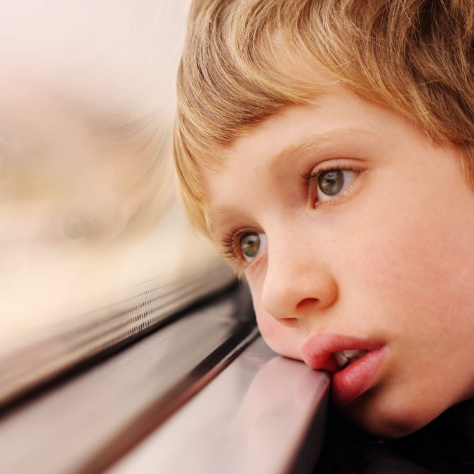 Young Boy with Head On Window Looking Outside