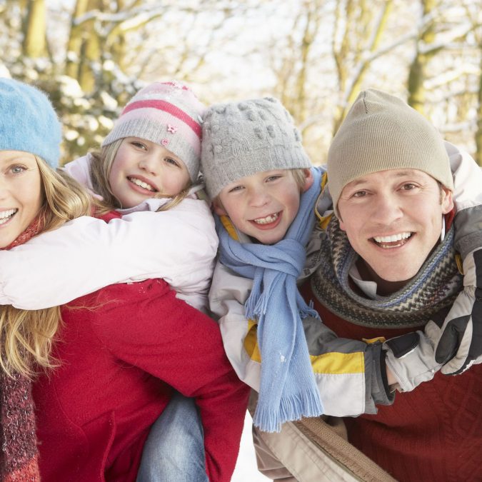 Father and Mother with Kids on Back Outside in the Snow