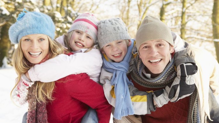 Father and Mother with Kids on Back Outside in the Snow