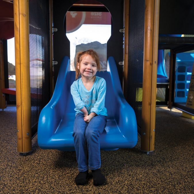 Little Girl Sitting on Slide in a Indoor Playplace