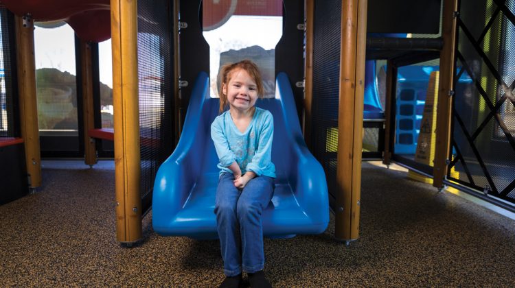 Little Girl Sitting on Slide in a Indoor Playplace