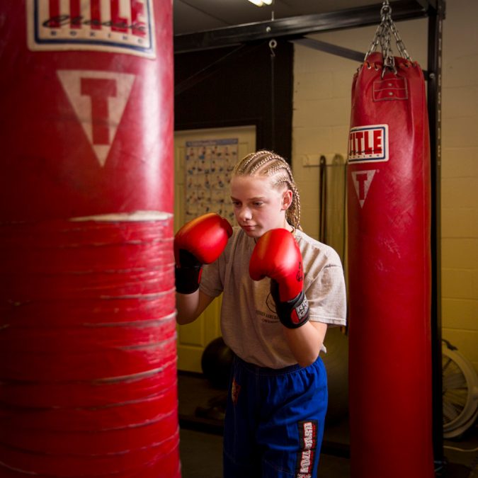 Girl with Punching Gloves Hitting a Punching Bag