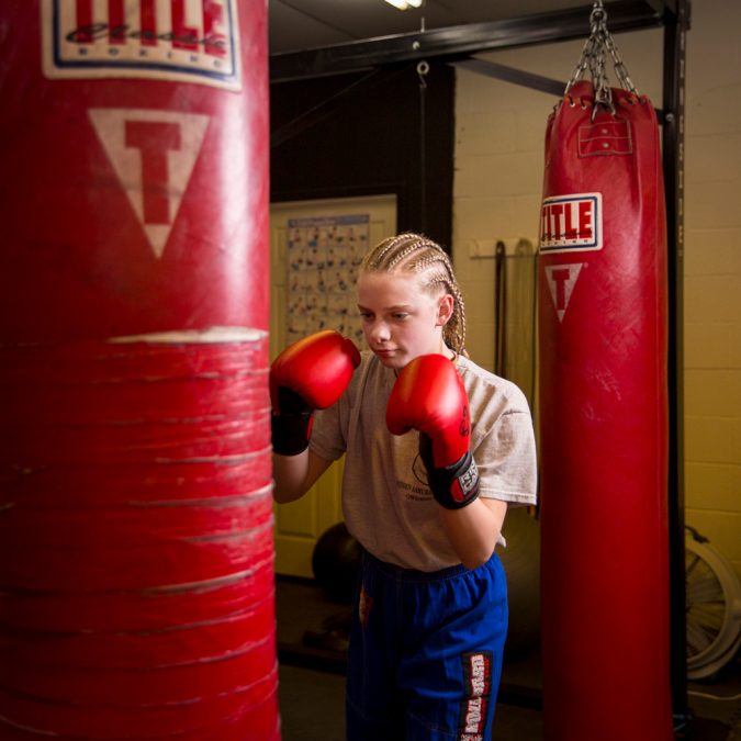 Girl with Punching Gloves Hitting a Punching Bag