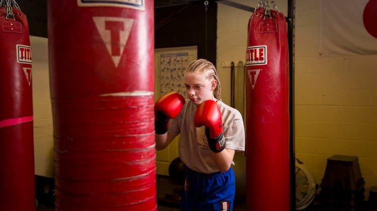 Girl with Punching Gloves Hitting a Punching Bag