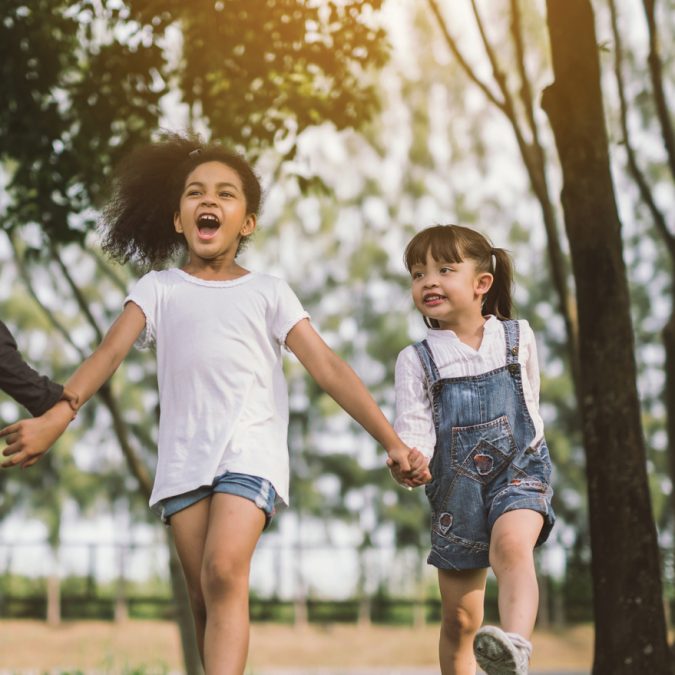 Two Little Girls Holding Hands and Walking Outside