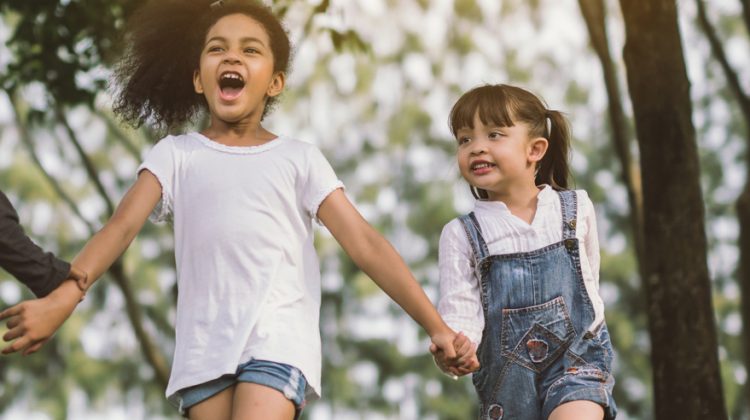 Two Little Girls Holding Hands and Walking Outside