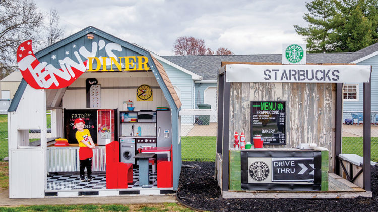 Four-year-old Tennyson Elder, posing in front of his diner and Starbucks playhouses.