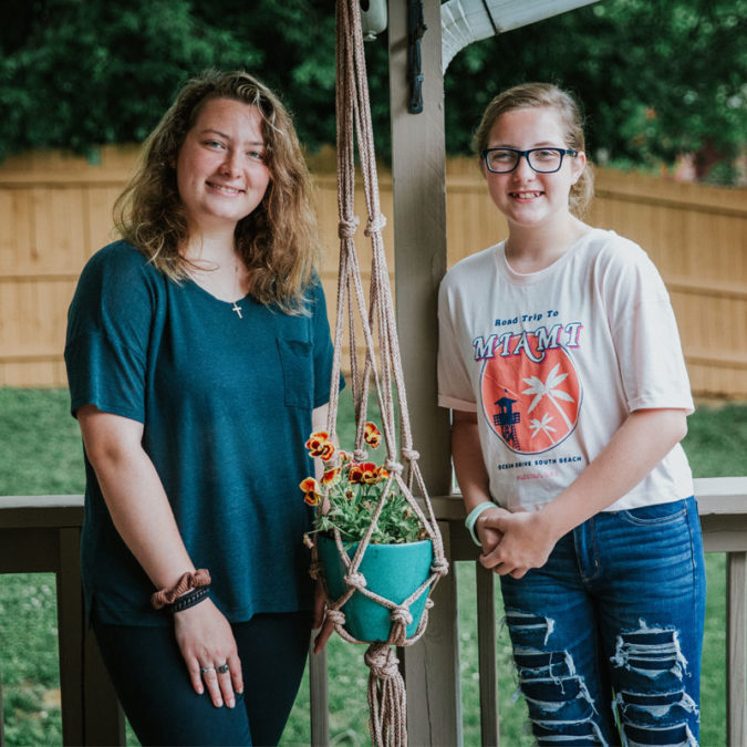 Girls smile next to their macrame pot holder