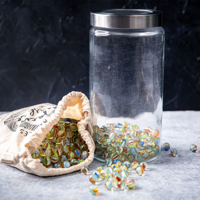 Glass jar and cloth bag filled with marbles