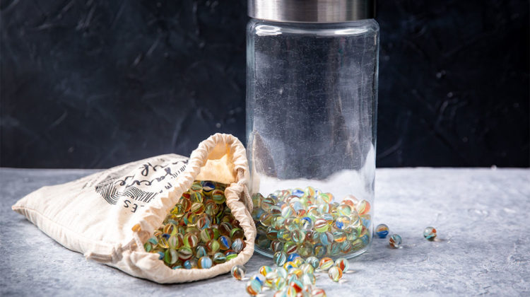 Glass jar and cloth bag filled with marbles