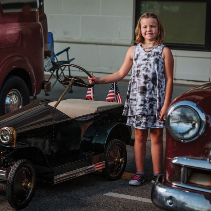 Bella Braden standing beside her restored car at a car show