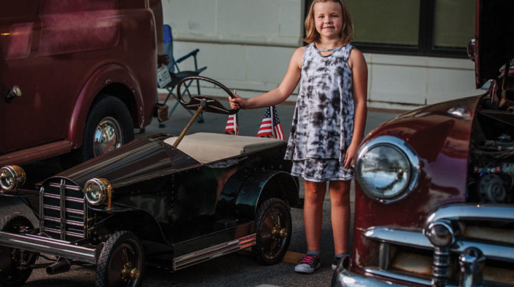 Bella Braden standing beside her restored car at a car show