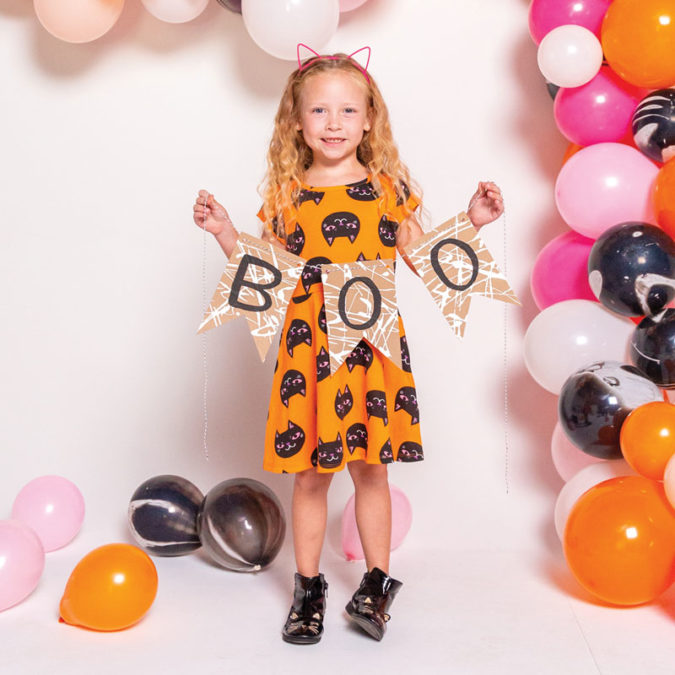 Little girl in cat ears holding "Boo" sign