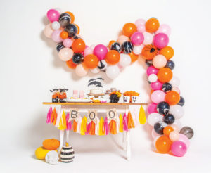 Halloween decoration on white background, including balloons, streamers, cake, and other snacks