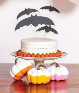 Halloween cake with paper bats on top and pumpkins below