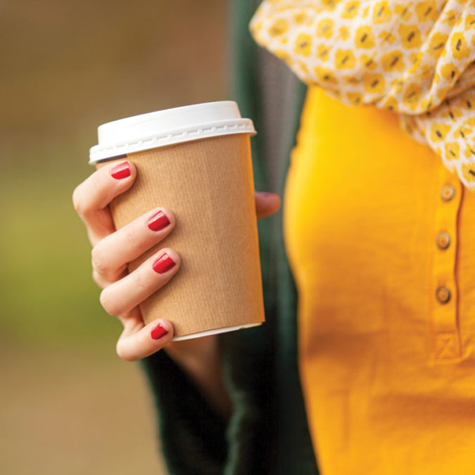 Woman holding coffee cup in autumn