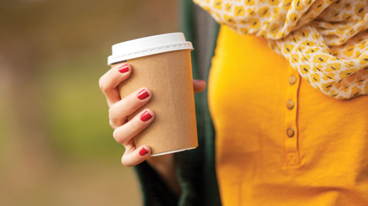 Woman holding coffee cup in autumn