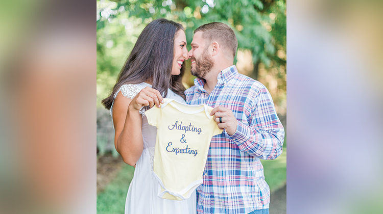 The Howards hold baby clothing that says "Adopting and Expecting"